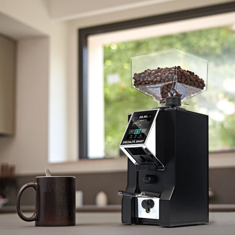 Coffee grinder with coffee beans and a mug on a kitchen counter